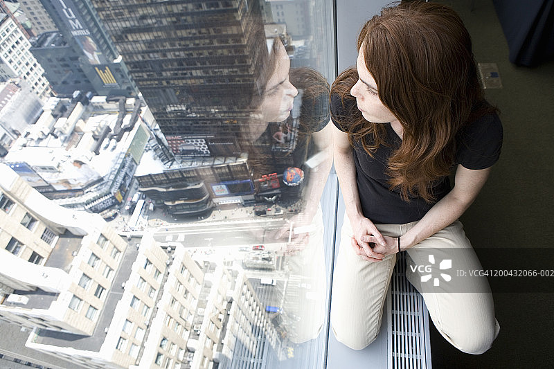 窗台上的女人俯瞰着城市，俯瞰着高架的风景图片素材