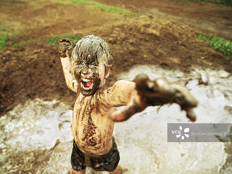 男孩(7-9岁)在泥，双臂伸展，肖像图片素材