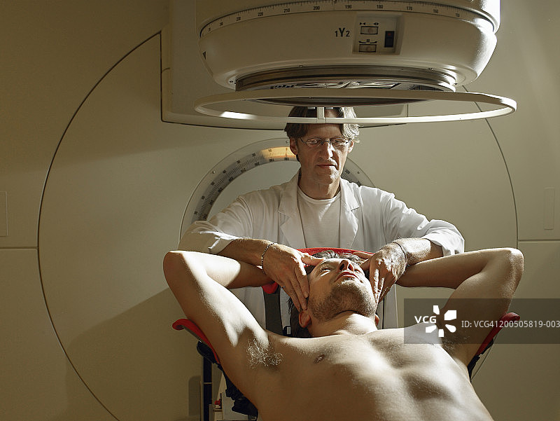 成熟的医生由男病人躺在放射床上图片素材