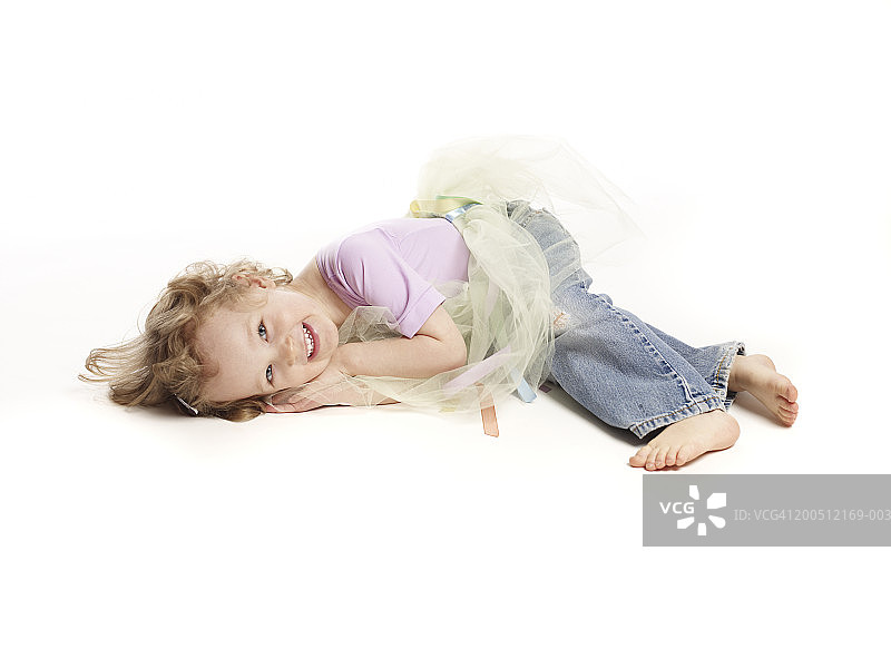 女孩(2-4)穿着芭蕾舞裙，躺在地板上，微笑着，肖像图片素材