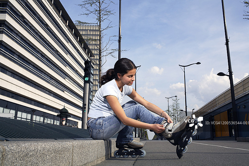 少女(14-16岁)坐在路边，穿着旱冰鞋图片素材