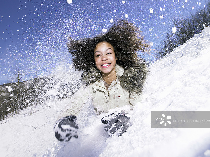 女孩(12-13)在雪中滚下山图片素材