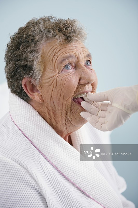 年长的女人在戴假牙图片素材