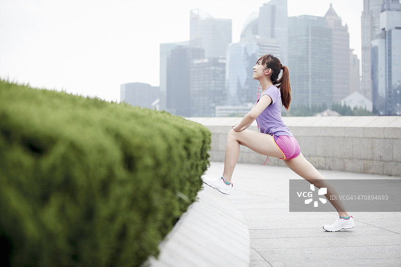 在中国上海，一名女性慢跑者正在伸展身体图片素材