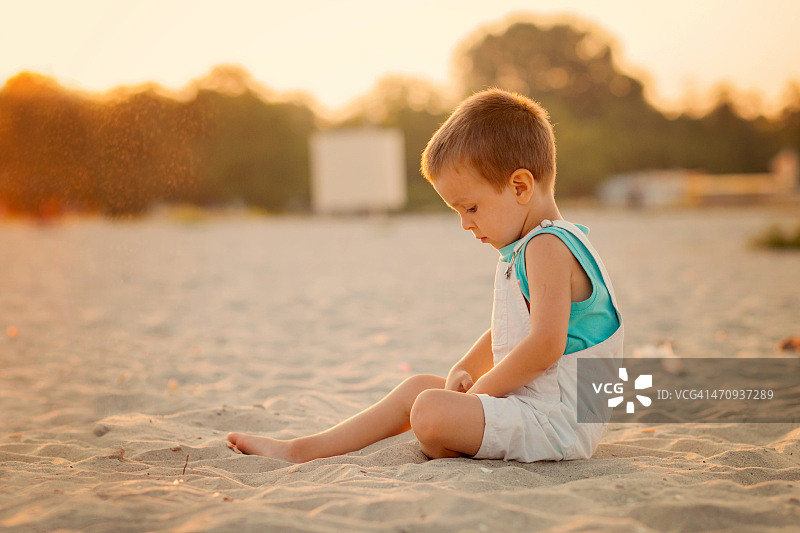 小男孩在沙滩上玩沙子图片素材