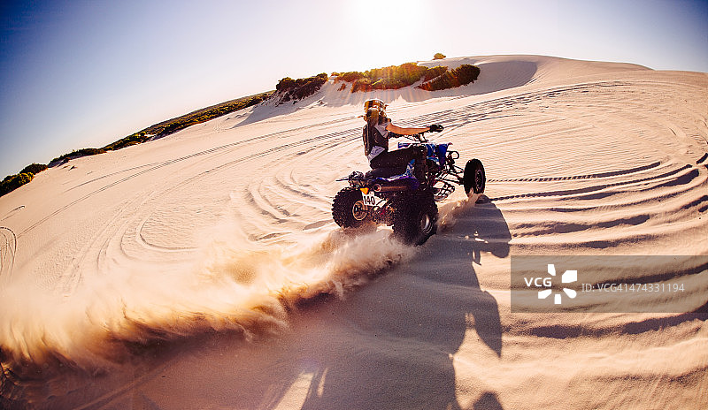 职业四轮摩托车手在沙丘上踢沙子图片素材