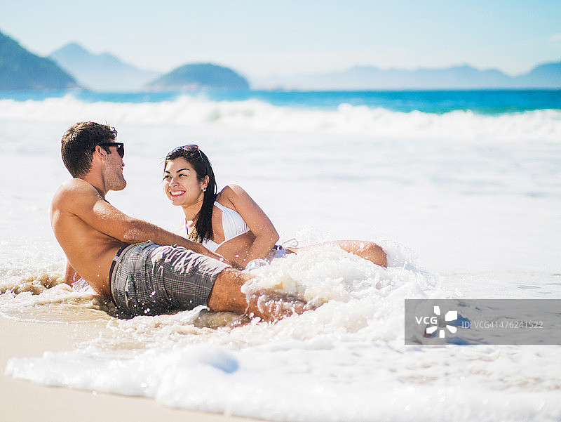 年轻幸福的夫妇一边聊天一边享受海滩。图片素材