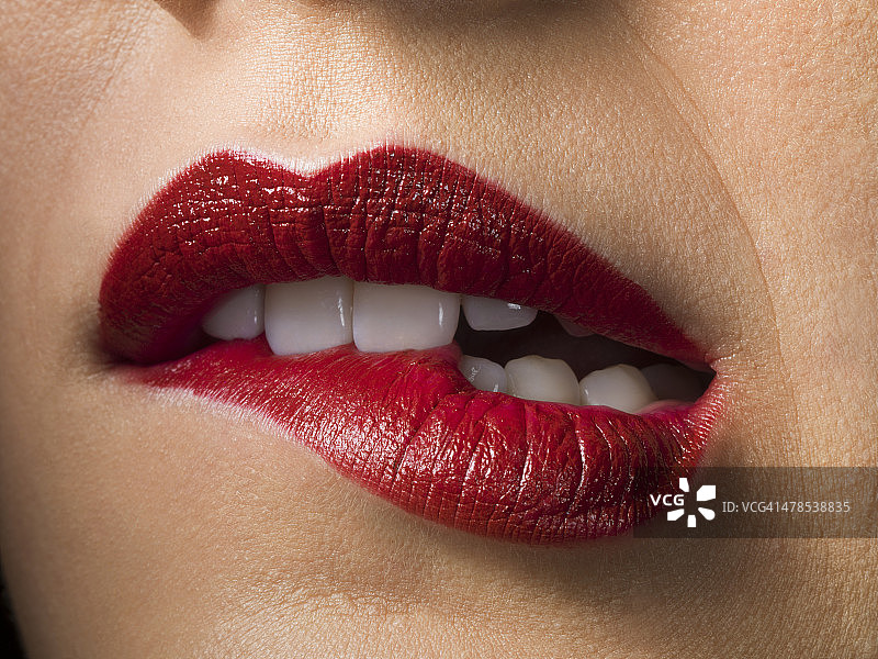 女性用红色唇膏，咬嘴唇，近距离图片素材