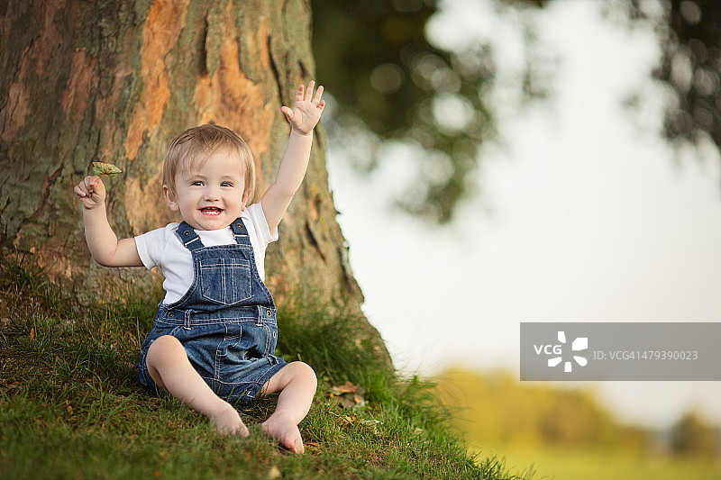 宝宝在树前挥手笑着图片素材