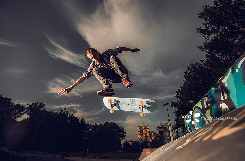 年轻的男性滑板运动员在对抗天空的行动。图片素材
