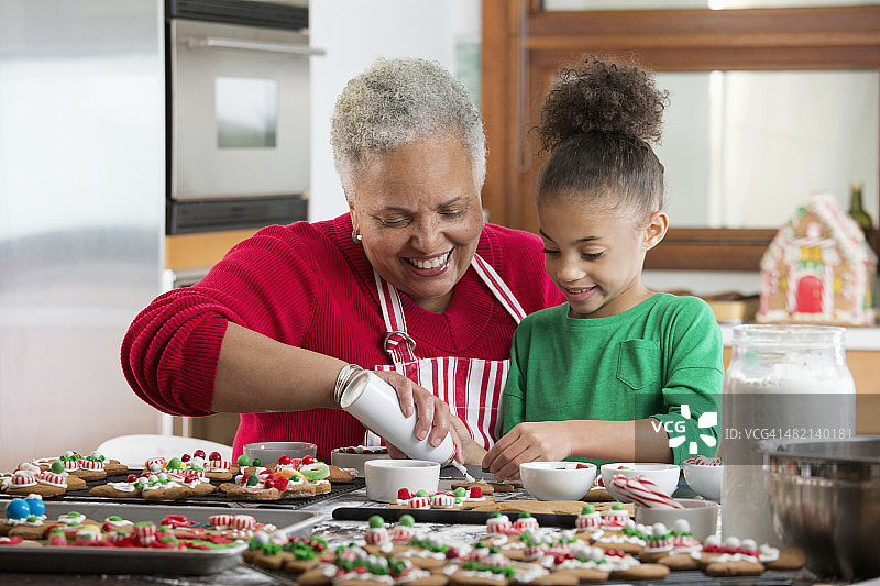 黑人妇女和孙女在厨房里装饰圣诞饼干图片素材