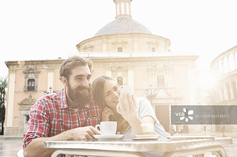 西班牙瓦伦西亚处女广场，一对年轻夫妇在路边咖啡馆喝咖啡图片素材