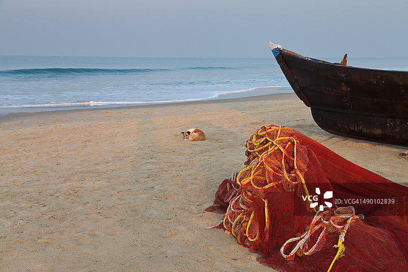 海滩上的渔船、渔网和狗。印度果阿。图片素材