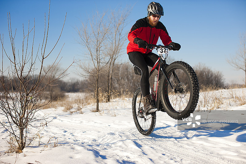 一个胖胖的骑轮胎的人在雪地里弹出一个轮子。图片素材