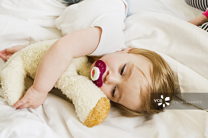 小女孩和泰迪熊一起睡觉图片素材