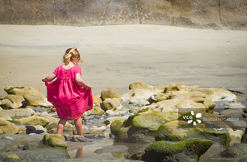 赤脚的小女孩在海滩的潮汐池图片素材