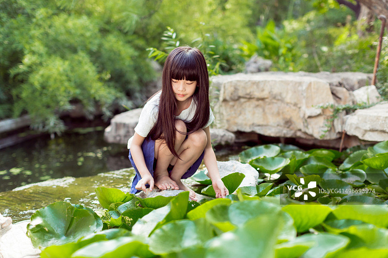 漂亮的小女孩在池塘里玩图片素材