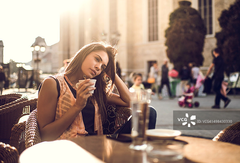 沉思的女人在城市的咖啡馆里放松，做着白日梦。图片素材