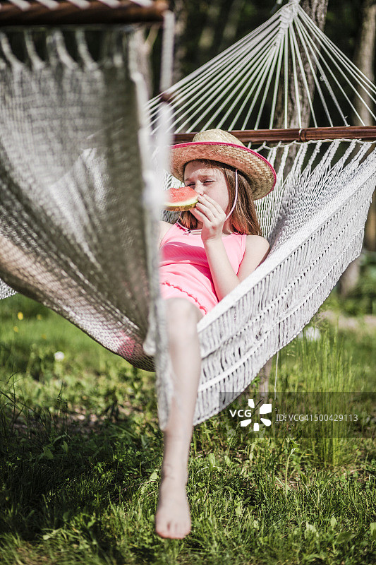 戴草帽的少女在吊床上吃西瓜图片素材
