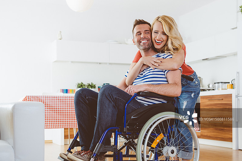 残疾人坐在轮椅上，他的妻子拥抱着他图片素材