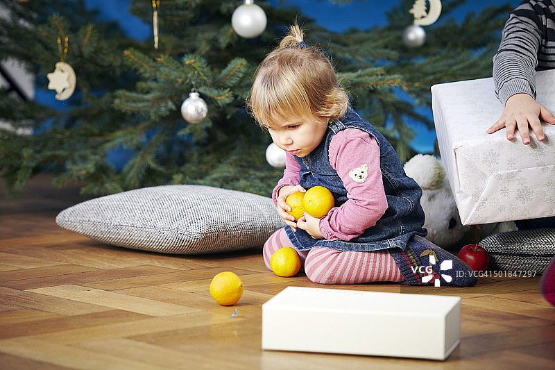 德国巴伐利亚慕尼黑，小女孩在玩柠檬，背景是圣诞树图片素材
