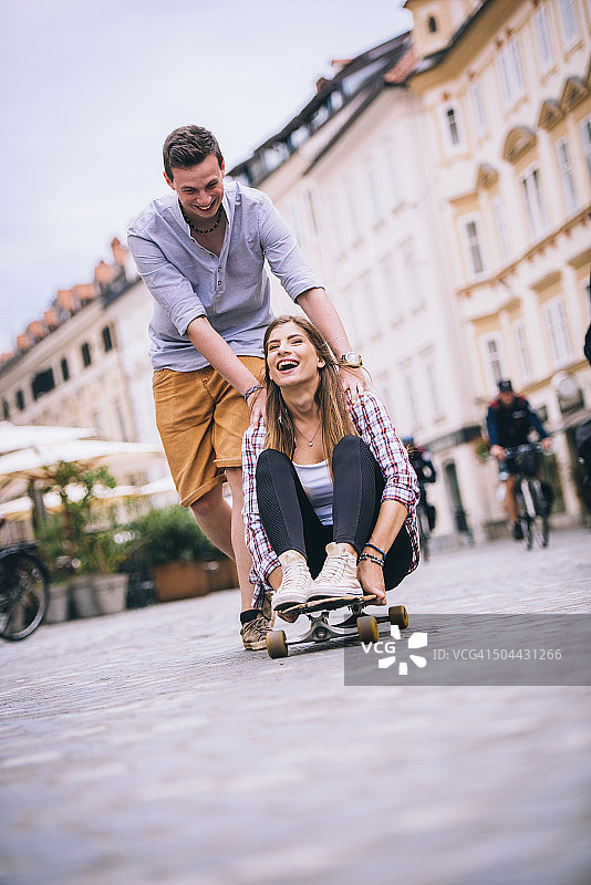 相爱的年轻夫妇在城市街道上玩滑板图片素材