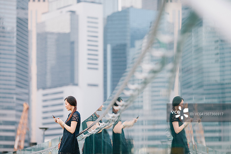 年轻的亚洲办公室女士在城市发短信图片素材