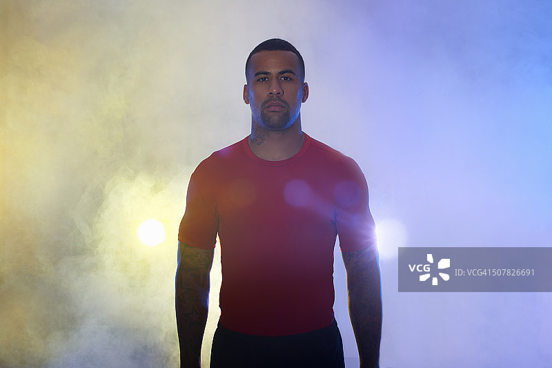 工作室肖像肌肉年轻的运动员在聚光灯和雾图片素材