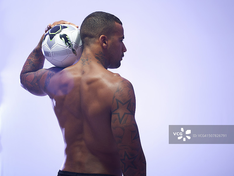 工作室拍摄的年轻男性足球运动员把球放在肩膀上图片素材