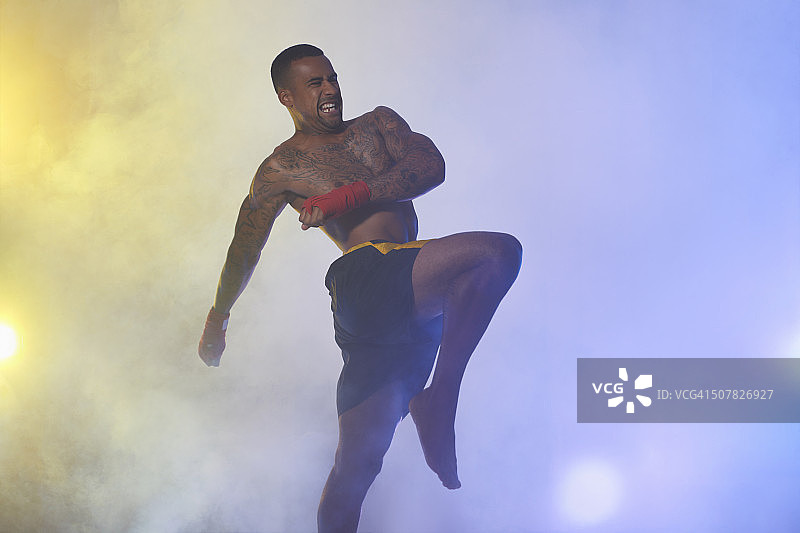 工作室拍摄的肌肉男性自由搏击运动员在聚光灯和雾图片素材