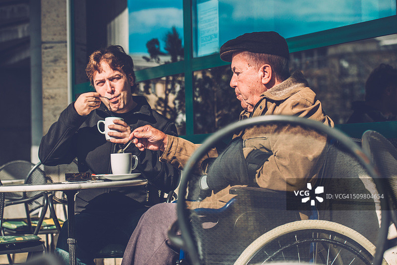坐在轮椅上的老人和喝咖啡的孙子，欧洲图片素材