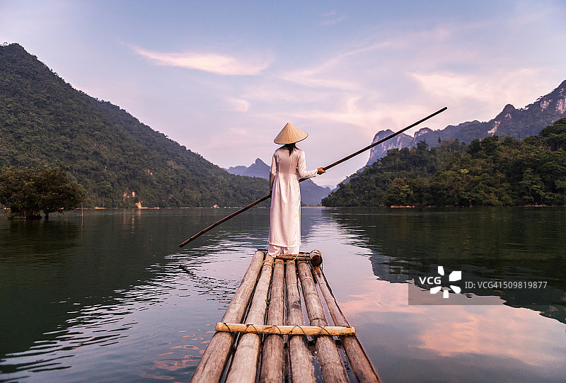 女人用竹筏撑过湖面图片素材