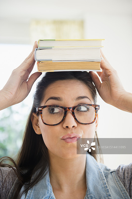 一个女人把一堆书顶在头上图片素材