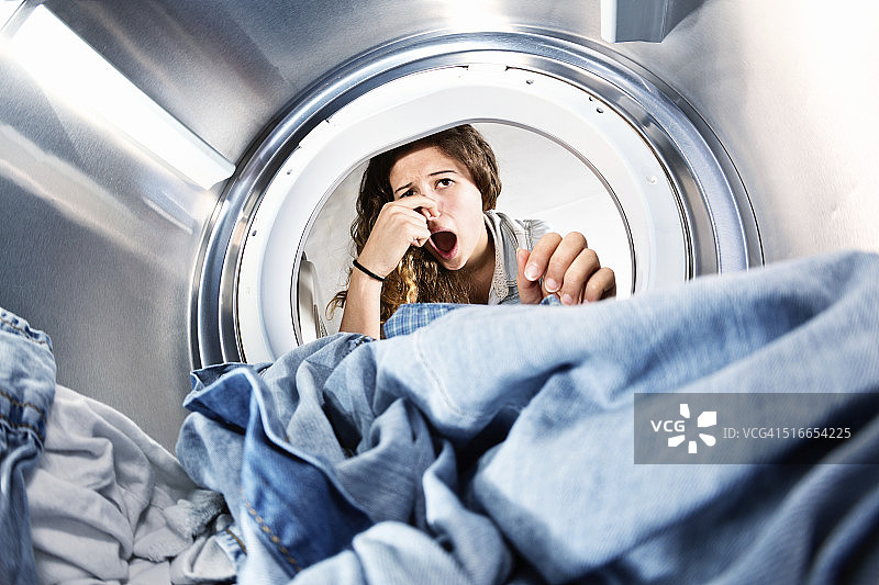 放在干衣机里的衣服很臭!不幸的女人捏着鼻子。图片素材