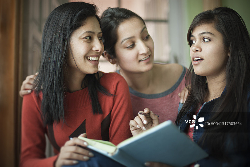 青少年晚期的快乐女孩学生一起学习一本书。图片素材