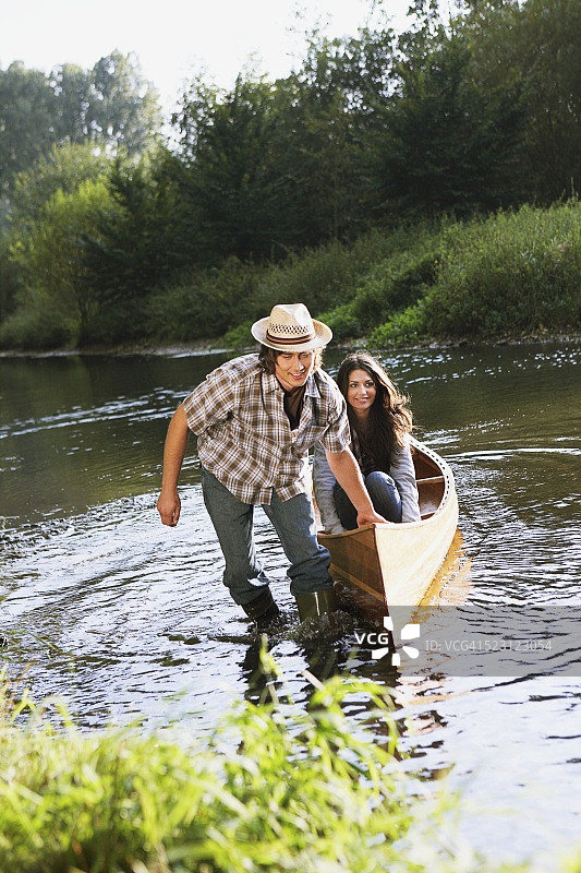 一个人把独木舟从河里拉上来图片素材