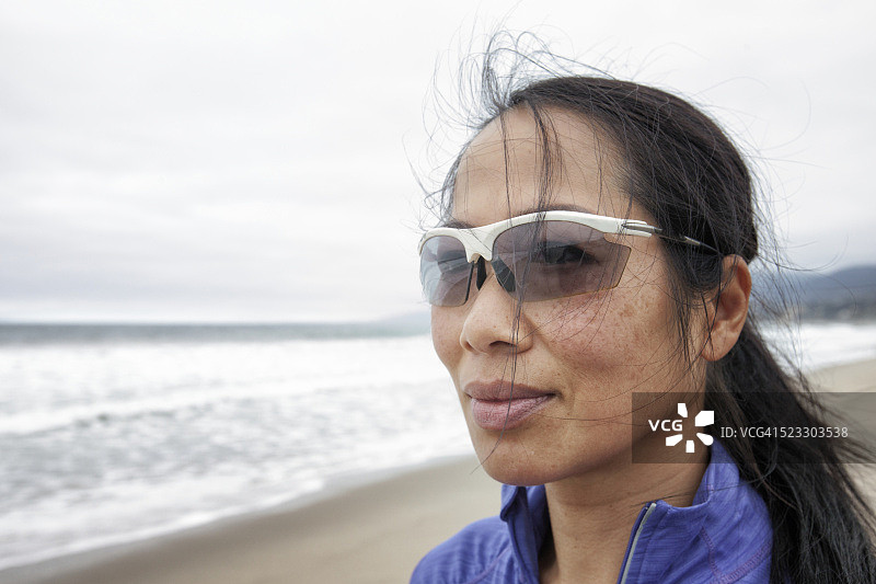 一位亚洲女运动员戴着太阳镜在沙滩上看向别处图片素材