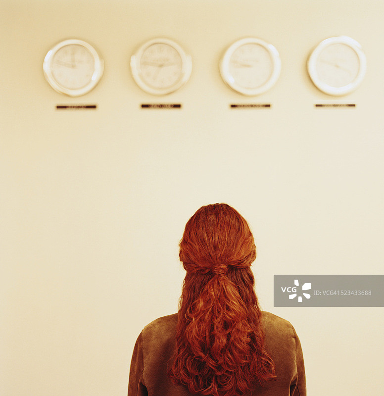 女人盯着被设置为不同时区的时钟图片素材