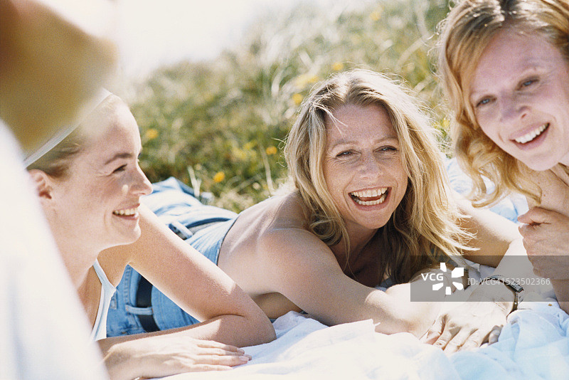 三个笑着躺在草地上的年轻女人图片素材