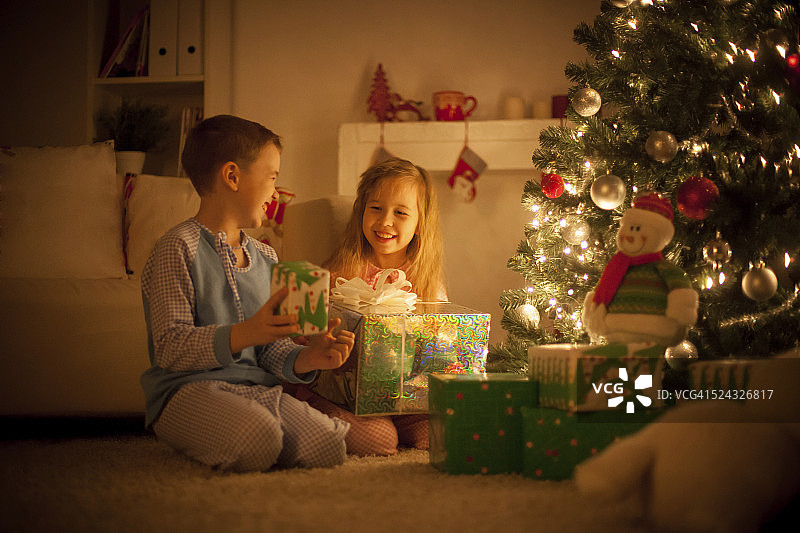孩子们在圣诞树旁拿着礼物图片素材