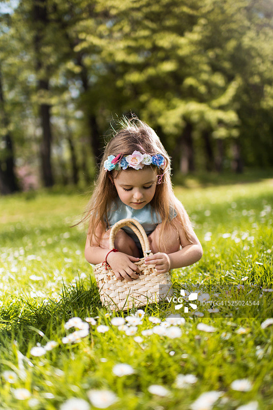可爱的小女孩在草地上摘花。图片素材