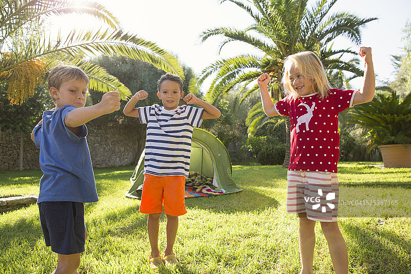 三个孩子在花园里秀肌肉图片素材