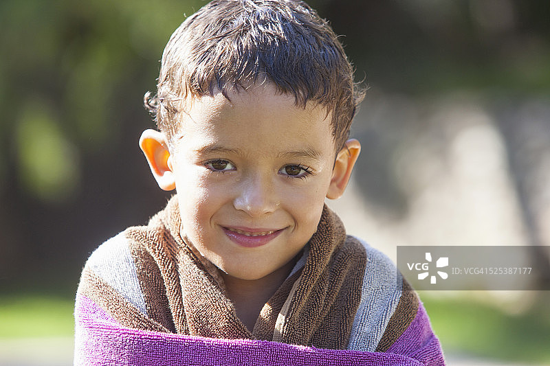 男孩的肖像湿头发包裹在毛巾在花园图片素材