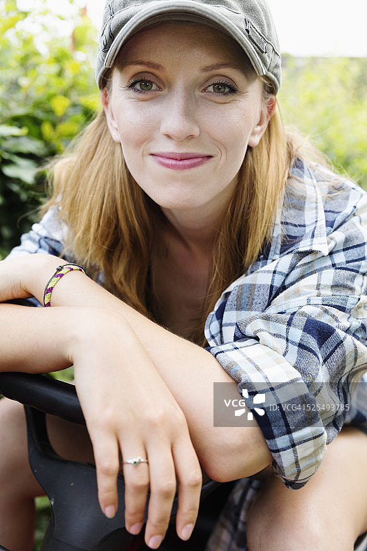 一个微笑的年轻女子坐在割草机上的肖像图片素材