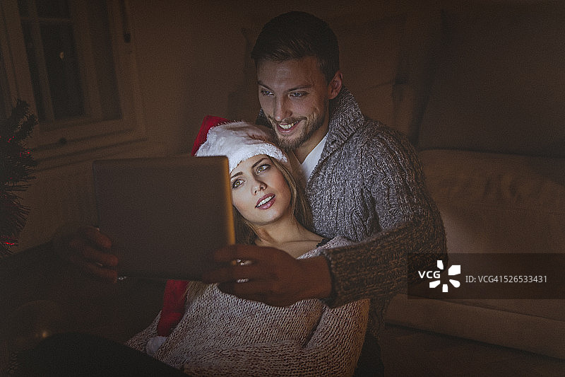 一对年轻情侣在圣诞夜用平板电脑相爱图片素材