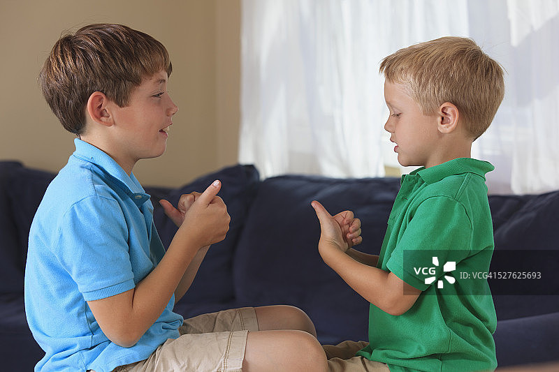 有听力障碍的男孩在沙发上用美国手语做运动图片素材