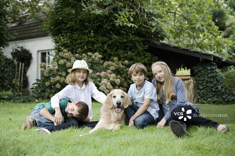 儿童(5- 6,7 - 9,10 -12)与狗在花园里图片素材