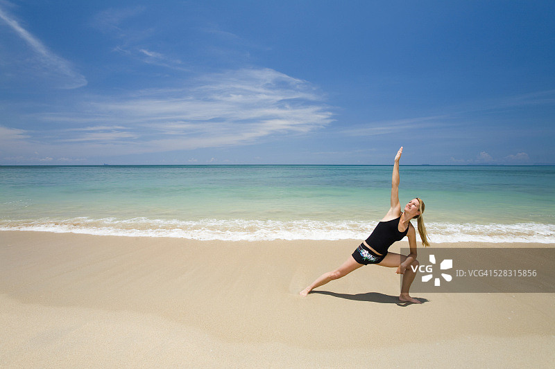 一名女游客在一个热带岛屿的海滩上做瑜伽;Koh Lanta泰国图片素材