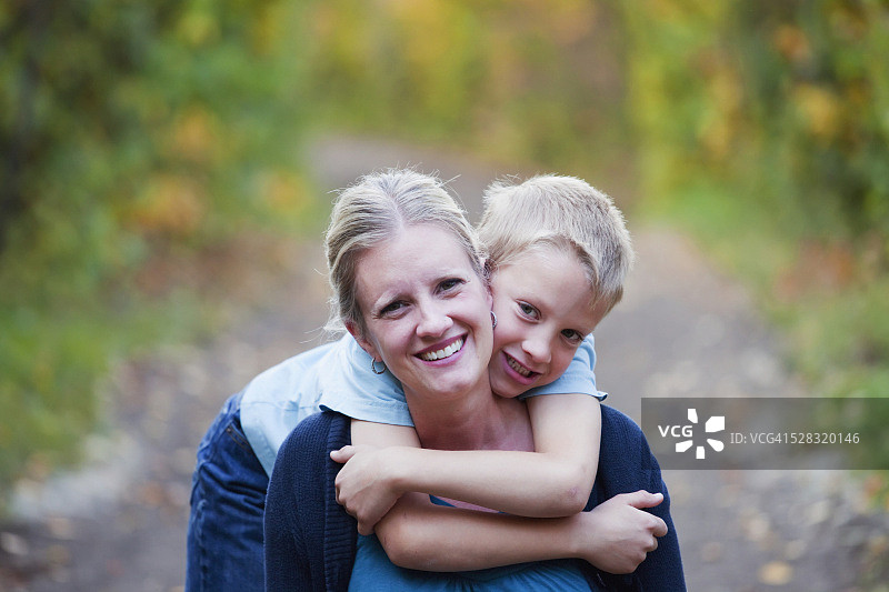 秋天，在公园小路上拥抱妈妈的小男孩;加拿大亚伯达省的埃德蒙顿图片素材