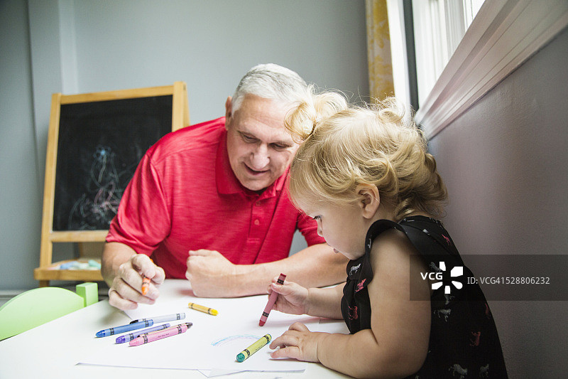 小女孩(12-23个月)和她的祖父坐在一起画画图片素材